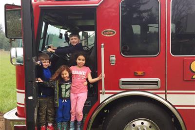 children standing inside a fire engine on a rainy day