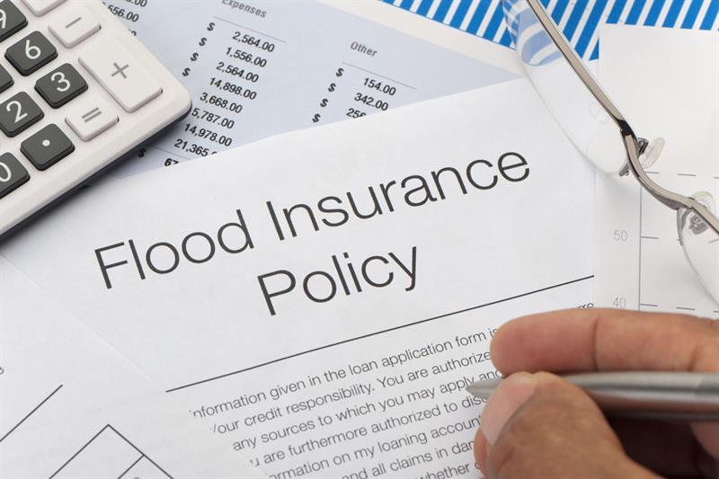 hand with pen over flood insurance policy papers