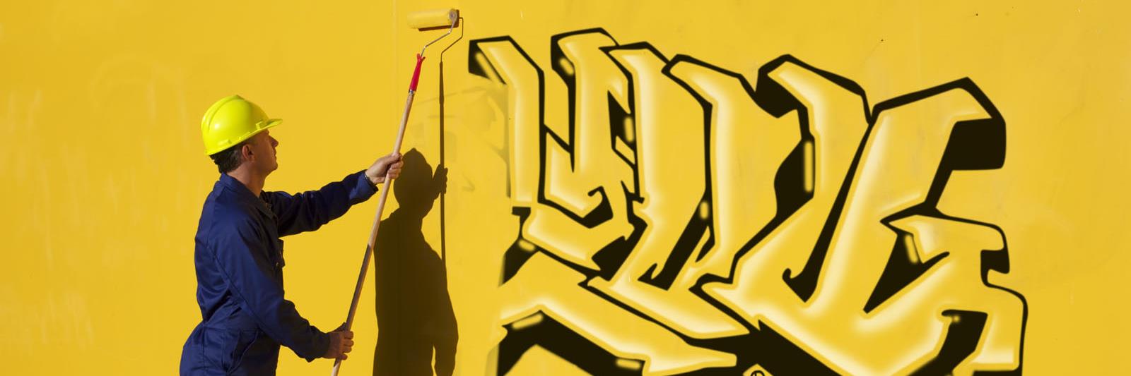man painting over wall graffiti