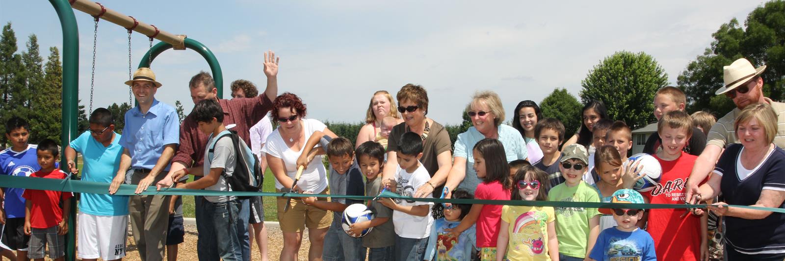 Residents and volunteers cutting the ribbon on new playground equipment at Bill Riegel Park