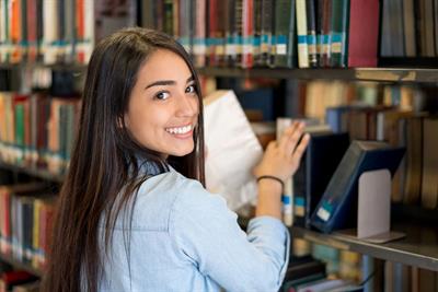 young-woman-shelving-books-looking-back-at-camera-smiling_web_1600x1067_color