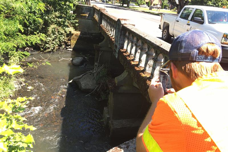 City employee collecting stream data at a bridge