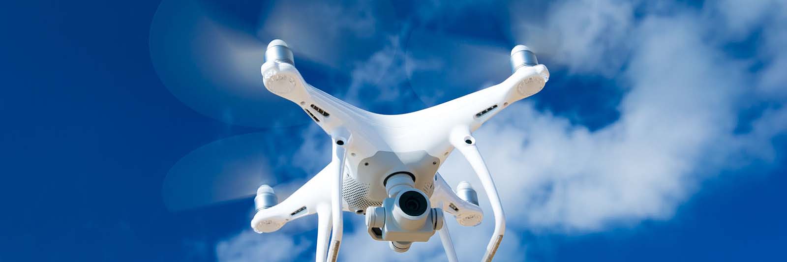 white-drone-hovering-in-a-bright-blue-sky_web_1600x533