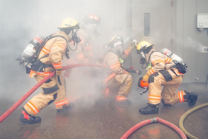 firefighters in full gear fight fire and smoke with hoses during training