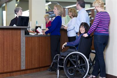 woman in wheelchair waiting in line at library counter