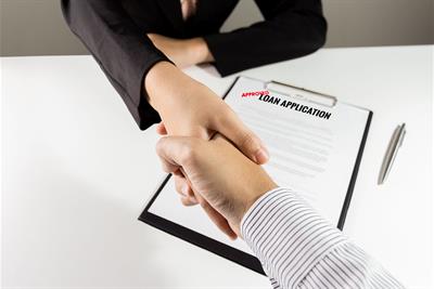 banker and customer handshake over approved loan application