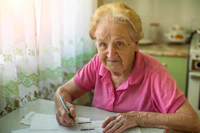 elderly woman fills out her utility bills