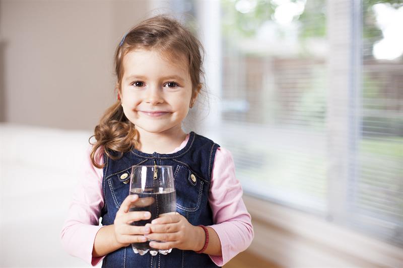 young girl holding glass of water facing camera